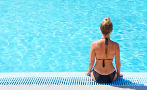 Young woman sitting on the ledge of the pool