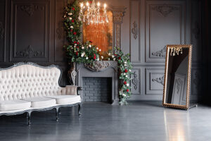 Black room interior with a vintage sofa, chandelier, mirror and fireplace decorated with flowers